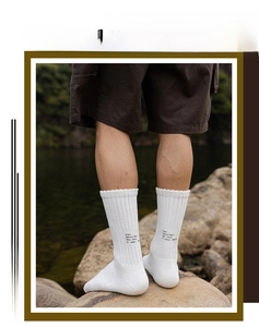 Close-up of white ribbed cotton socks featuring black text print in an outdoor setting
