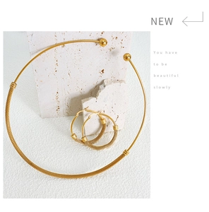 Detailed view of golden mesh texture collar necklace and earrings on stone background