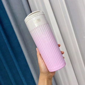 Pink gradient stainless steel travel coffee mug with textured grip shown in hand