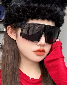Close-up of oversized black retro cycling sunglasses with thick frames and dark lenses