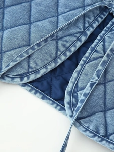 Detailed macro view of quilted washed denim fabric with diamond stitching and soft lining