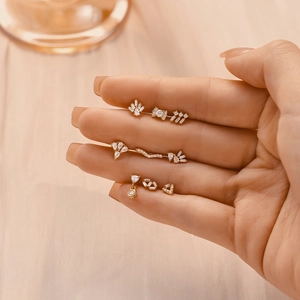 Macro view of gold silver cartilage earrings with CZ tassels and flat back studs on hand