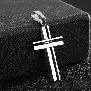 Detail of silver hollowed out double-layer cross pendant on a textured dark base
