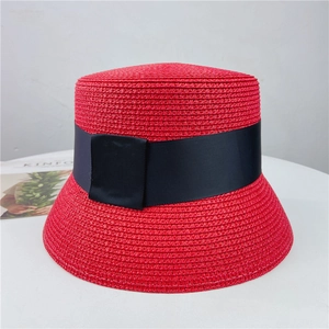 Detail of red woven straw sun hat featuring a black grosgrain ribbon and bow detail