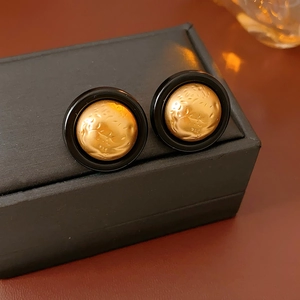 Macro shot of vintage round gold hammered texture earrings with black resin trim