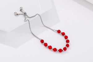 Détail du bracelet en perles de marbre rouge avec chaîne réglable en argent et métal
