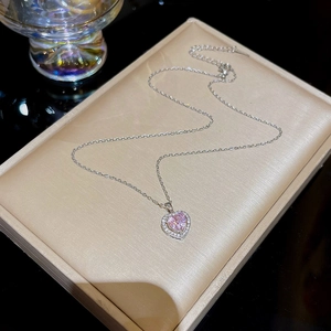 Detailed macro view of a silver heart necklace with pink stone in a luxury jewelry gift box