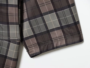 Detail of plaid trench coat fabric with precision stitching and woven check pattern