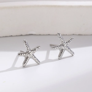 Detailed macro shot of silver starfish ear cuffs with realistic textured metal finish