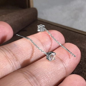 Dettaglio di orecchini a filo in argento con una pietra rotonda di zircone scintillante