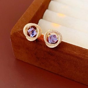 Macro di orecchini dorati con gemma geometrica viola e bordo in micro-pavé di diamanti