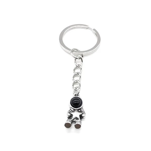 Vintage silver astronaut keychain with black visor and star detail on white background