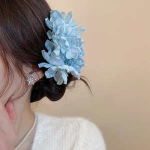 Detail of blue fabric flower hairpin with gradient organza petals and pearl necklace