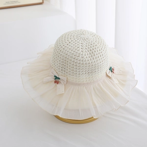 Detail of girls straw hat featuring chiffon pleated brim and red cherry ornaments