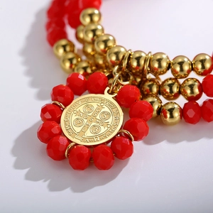 Detailed macro view of red faceted beads and golden Saint Benedict medal on a bracelet