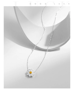 Macro shot of S925 silver daisy pendant with white enamel petals on a minimal background