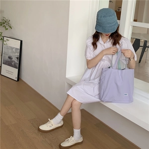 Foto lifestyle de bolso de lona lila con vestido blanco de mangas abullonadas chic