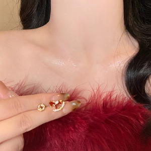 Detailaufnahme asymmetrischer Goldohrringe mit rotem Fledermausdesign und Zirkonia