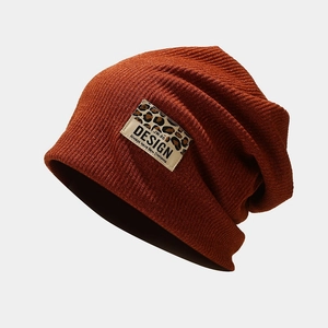 Gros plan du bonnet en maille caramel avec écusson léopard et broderie DESIGN