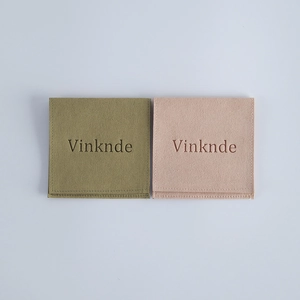 Detailed view of square microfiber jewelry pouches in olive green and light pink with logo