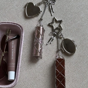 Macro detail of silver mesh lipstick holder charm with heart and star metal pendants