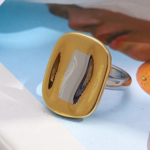 Detail of bicolored geometric ring featuring a 18K gold plated rectangular face and silver band