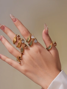 Detail of gold open rings featuring teardrop cubic zirconia and turquoise enamel inlay