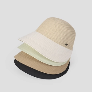Detalle de cuatro sombreros de paja apilados en colores beige, verde, canela y negro.