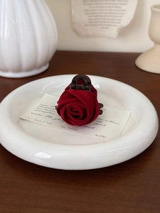 Detailed close-up of a deep red rose hair claw clip made of silky satin material