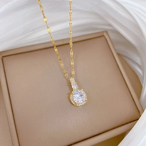 Détail d'un collier plaqué or avec pendentif rond en zircon sur un tissu en satin blanc