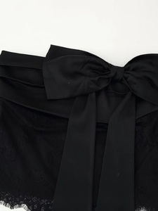 Détail d'une jupe en satin noir avec dentelle délicate et un grand nœud décoratif