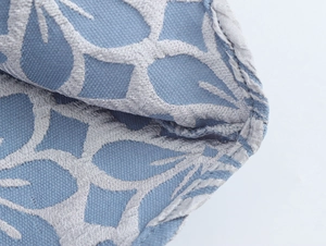 Makroaufnahme von blauem Webstoff mit silbernem Jacquard-Blattmuster und sauberer Naht