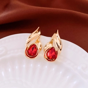 Macro shot of vintage teardrop red crystal earrings with gold finish on a ceramic plate