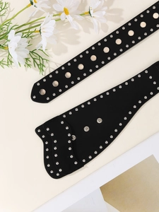 Detailaufnahme eines schwarzen Ledergürtels im Punk-Stil mit silbernen Nieten und Ösen