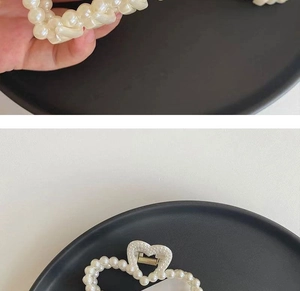 Detail view of heart-shaped pearl hair claw clip with gold metal spring and cream pearls