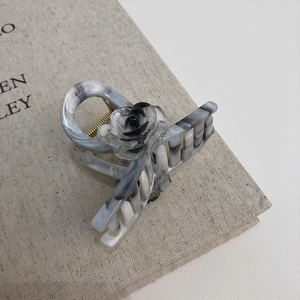 Elegant ice gray marble hair claw clip with a black rose accent on an aesthetic book