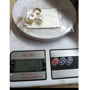 Detailed view of baroque pearl hoop earrings on a scale showing 10g weight