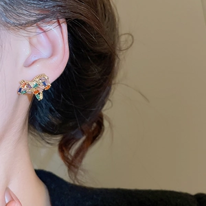 Detailed side view of a model wearing colorful geometric zircon stud earrings in gold