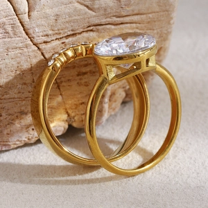 Detail of 18K gold-plated double rings with oval zircon on a natural stone background