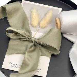 Sage green and white handmade frayed edge chiffon ribbons on a black decorative tray