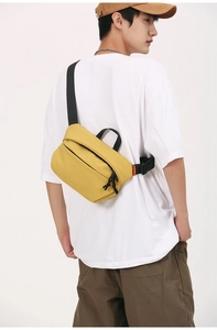Side view of a yellow nylon crossbody bag worn by a model against a white background