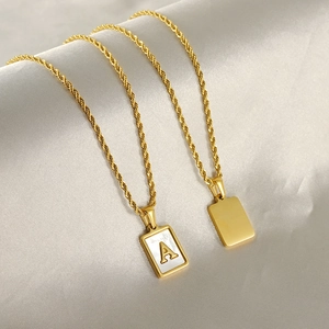 Detailed macro view of 18k gold rectangular pendant with mother of pearl A and twist chain