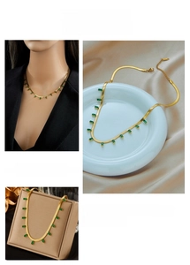 Detail of gold flat snake chain necklace with rectangular emerald green gemstones