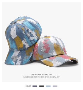 Detail of washed denim baseball caps with distressed holes and paint splatter design