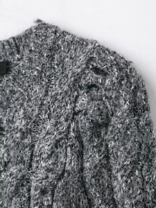 Close-up of gray knit cardigan fabric featuring puffy sleeves and mosaic texture