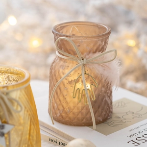 Amber textured glass Christmas candle holder with feather bow and metal pendant on books