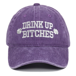 Close-up of "DRINK UP BITCHES" white embroidery on a purple washed cotton baseball cap.