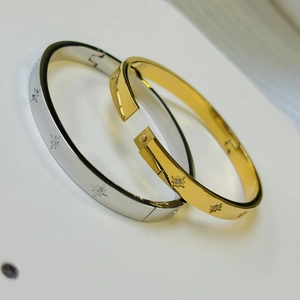 Macro detail of 18K gold and silver star engraved bangles with cubic zirconia stones