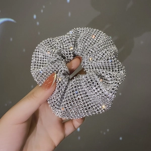 Close-up of a silver-toned metal hair clip with shimmering rhinestones and starry lighting