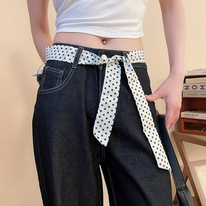 Dettaglio di jeans a gamba larga blu scuro con cintura a foulard a pois bianchi e neri